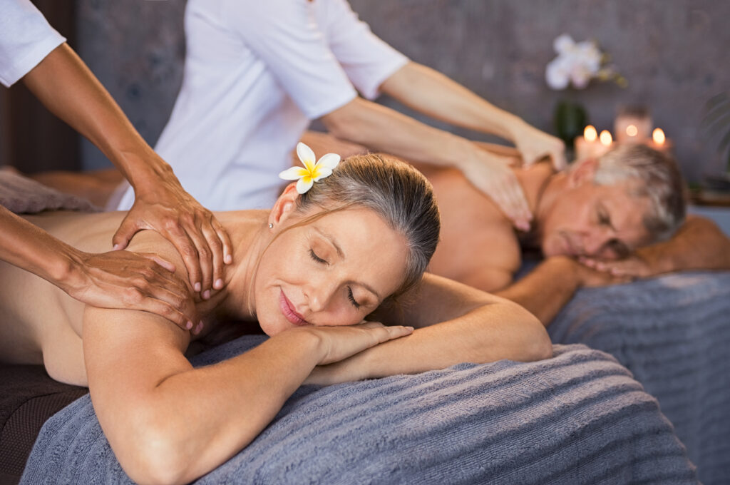 Senior couple in spa salon getting massage. Relaxed senior couple enjoying body treatment in a wellness center. Retired man and woman receiving a back massage from masseur in a spa salon.